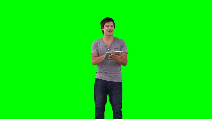 一个男人在绿色背景下用平板电脑控制虚拟屏幕