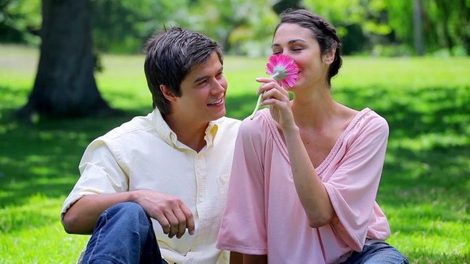 一个微笑的男人给他在乡下的女朋友一朵粉红色的花