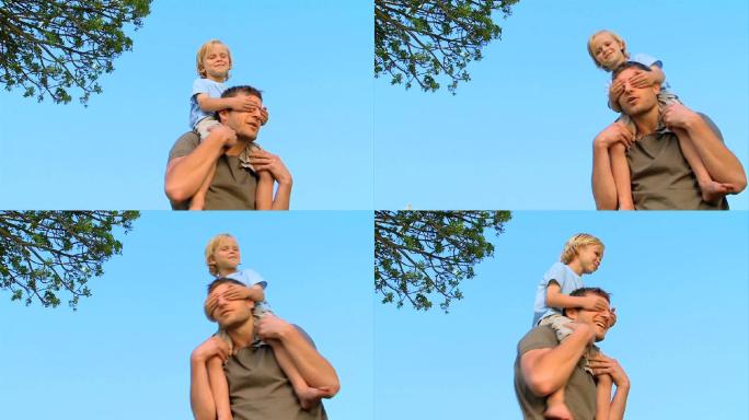 父亲把儿子扛在肩上在公园里