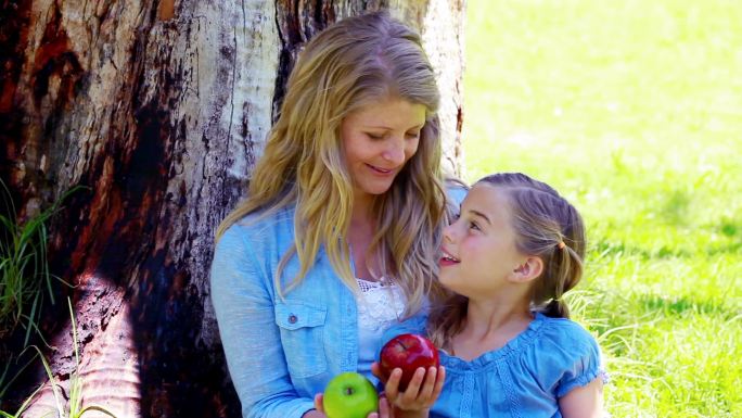 妈妈和女儿在公园里拿着苹果