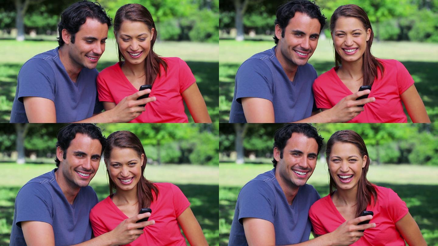 一对幸福的情侣在公园里看手机