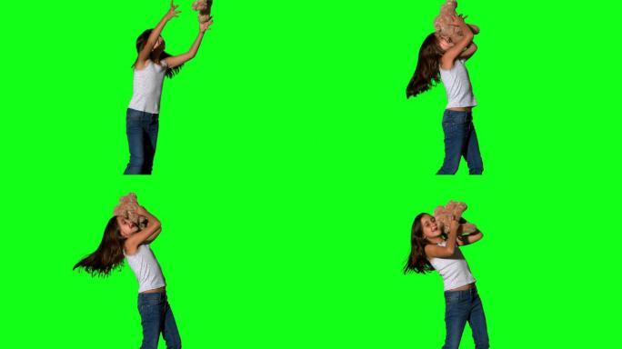 在绿色屏幕上的慢动作中，小女孩投掷并抓住泰迪熊