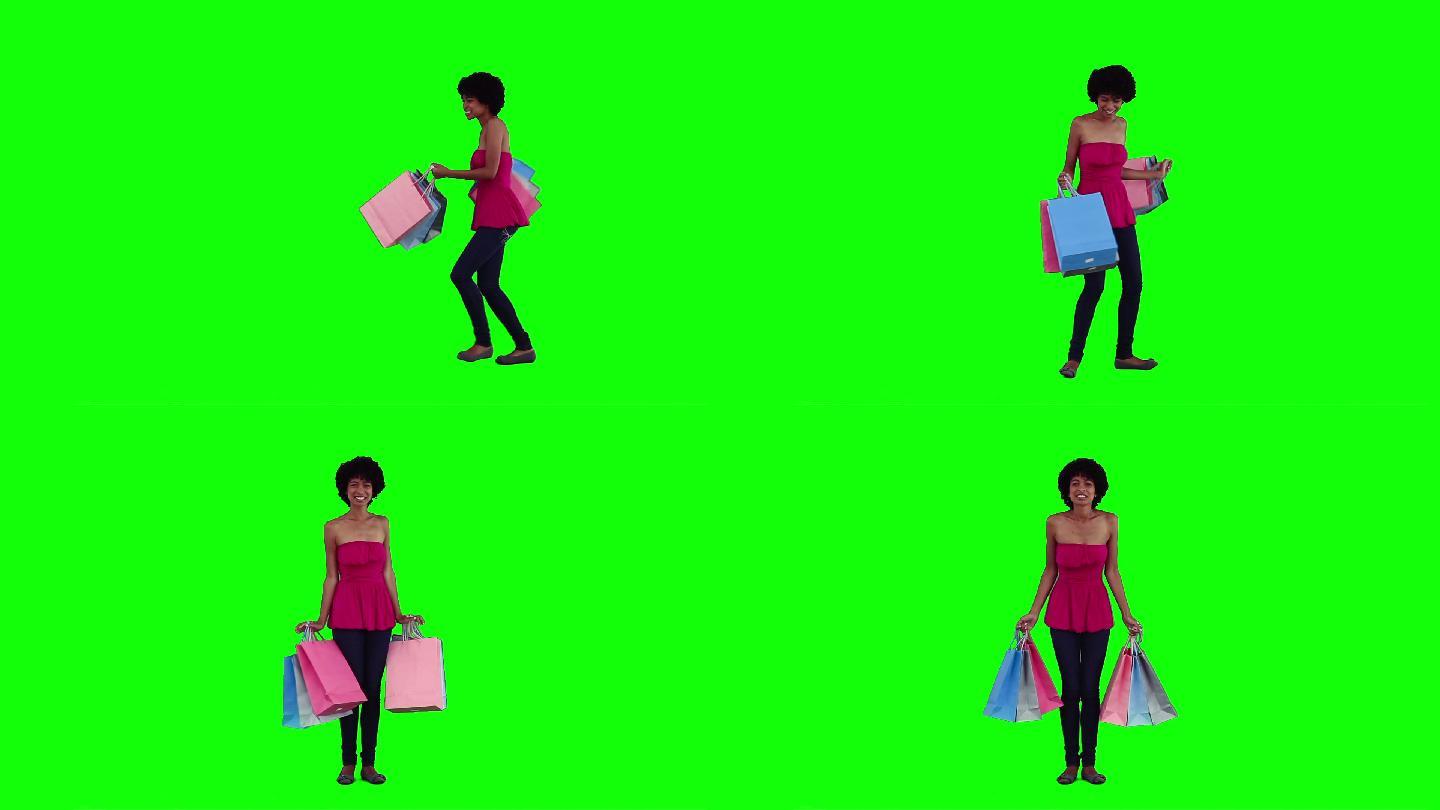 一个快乐的女人拿着购物袋，背景是绿色的
