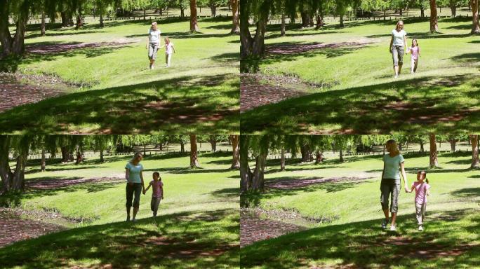 妈妈牵着女儿的手在公园里散步