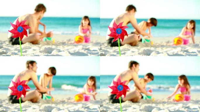 爸爸帮他的孩子们在海滩上做沙堡