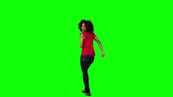 一个快乐的女人在绿色的背景下跳舞