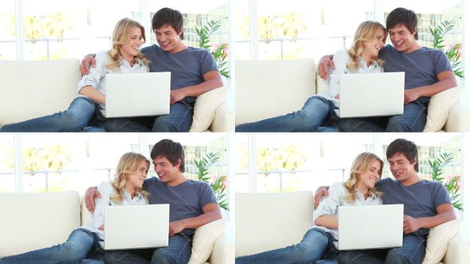 一对快乐的夫妇在客厅里看笔记本电脑