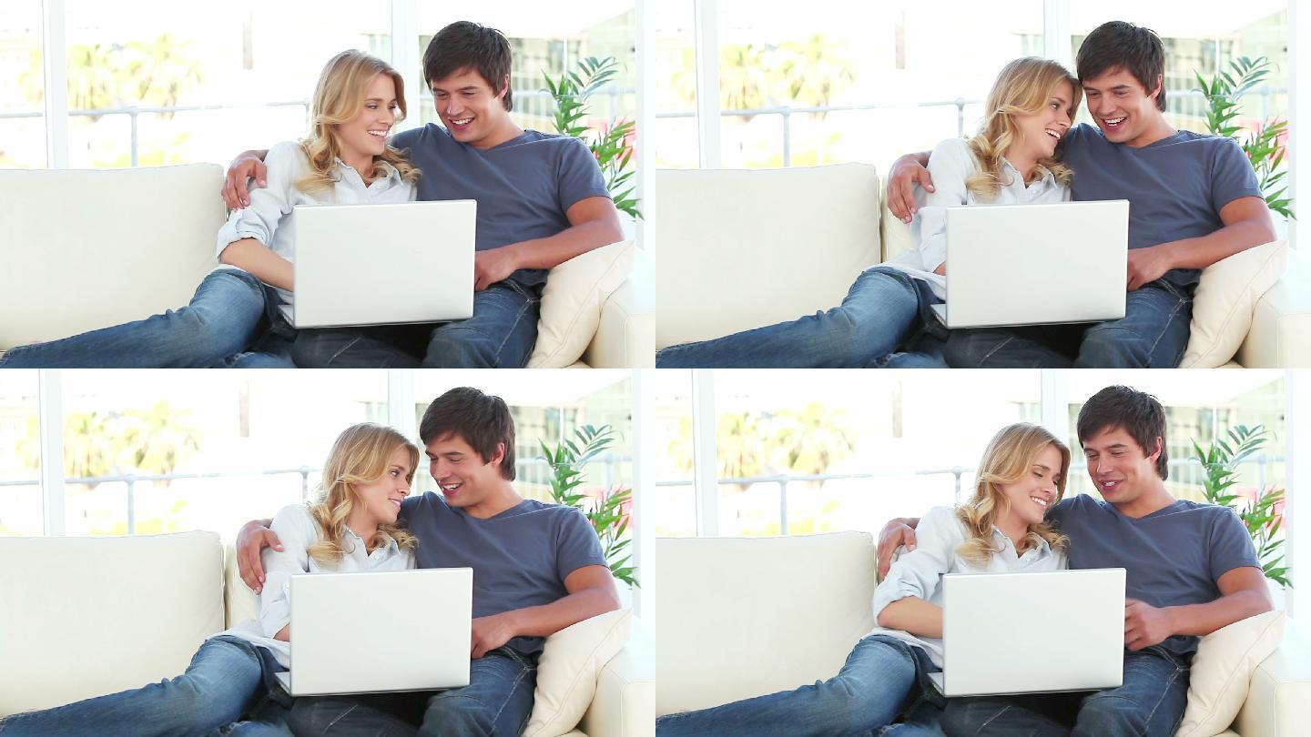 一对快乐的夫妇在客厅里看笔记本电脑