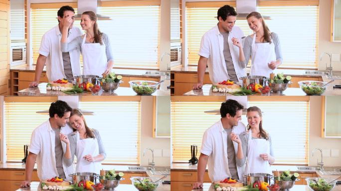 丈夫品尝他的妻子在厨房用勺子做饭