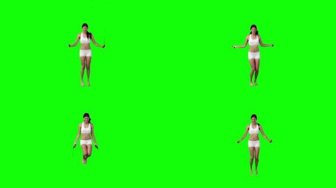 一个亚洲女性跳绳，在绿色背景下
