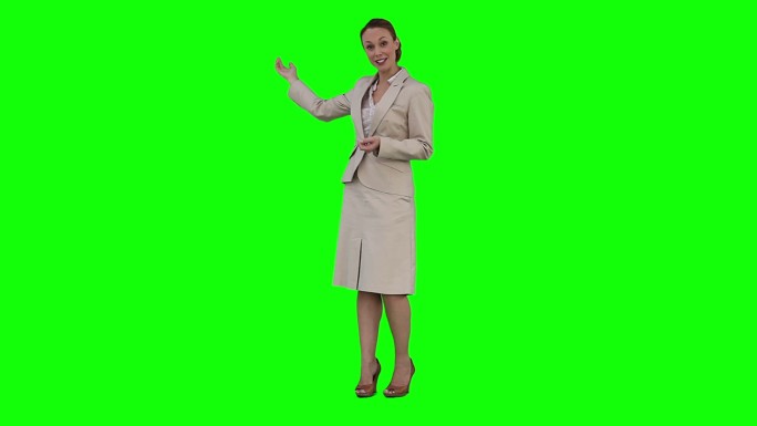 一位女商人正在绿色背景前做一个虚拟演示