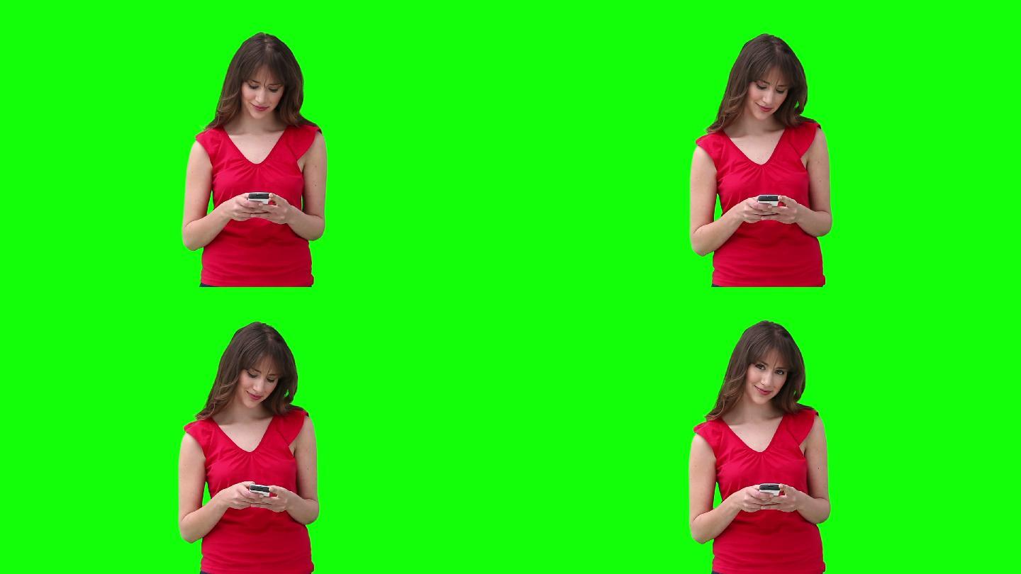 一名女子在绿色背景下看摄像头前正在写短信