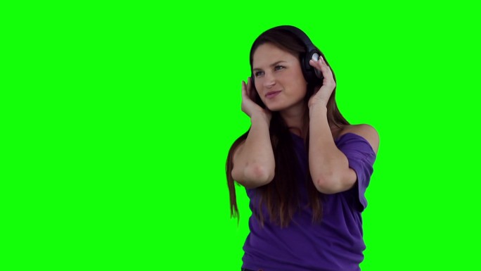 女人戴着耳机听音乐，在绿色背景下跳舞