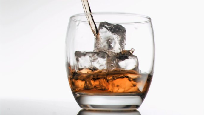 以超慢动作将苏格兰威士忌倒入加冰的玻璃杯中