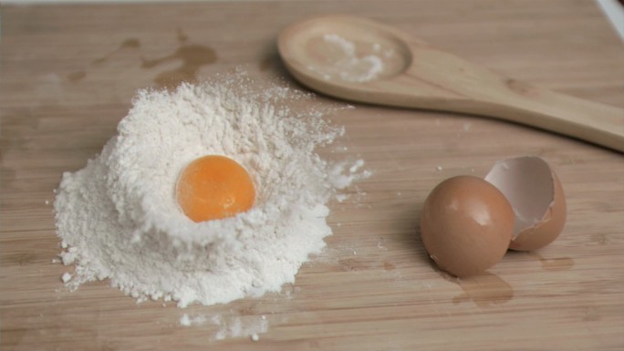 在厨房的桌子上，用超慢的动作把鸡蛋放在面粉上