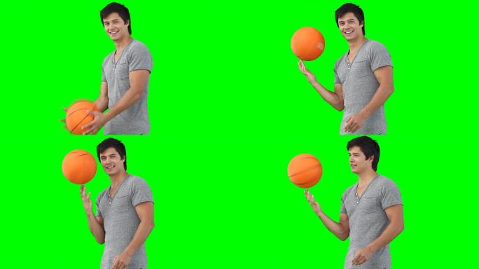 一个人在绿色的背景下用手旋转着篮球