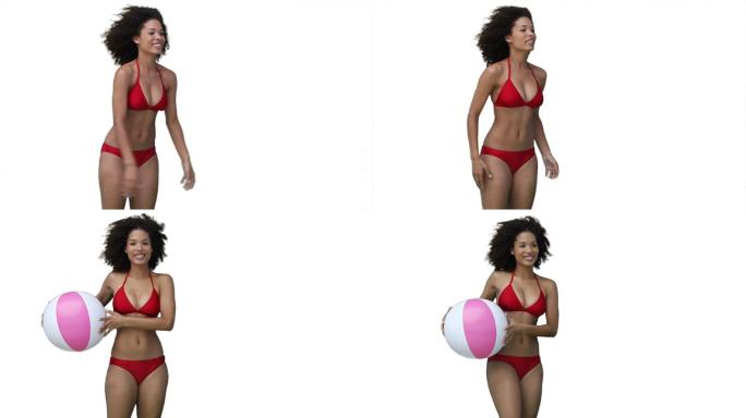 女人玩沙滩球在她的比基尼对一个白色的背景