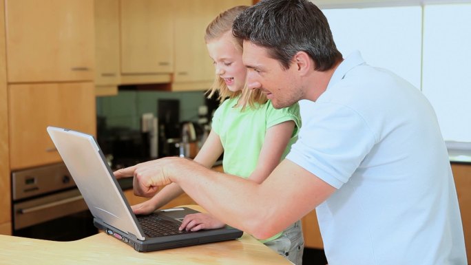 父亲和女儿在厨房里使用笔记本电脑