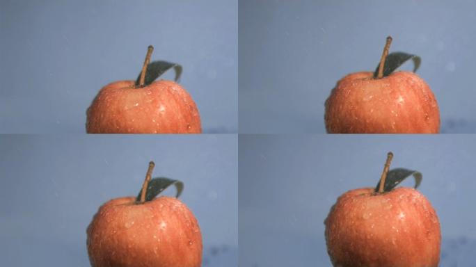 水落在红苹果上慢镜头，在蓝色背景下