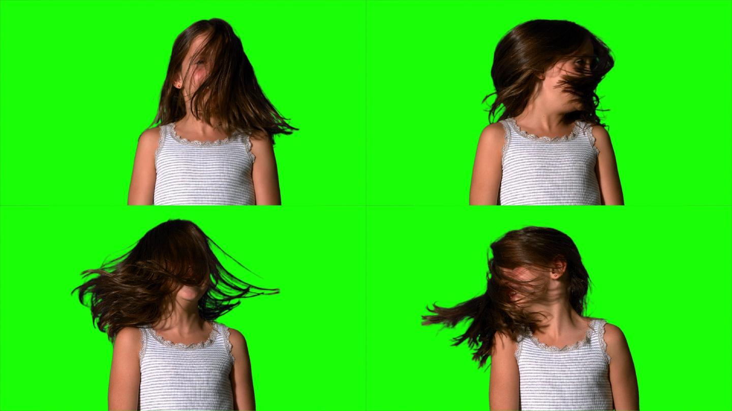 在慢动作的绿色屏幕上，小女孩摇着她的头发
