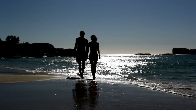 一对可爱的情侣在月光下漫步在海滩上