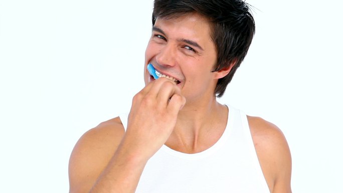 在白色背景下刷牙的男人