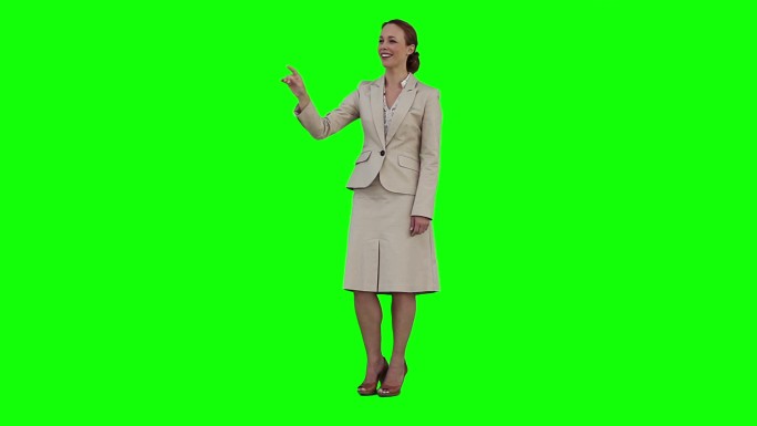 一位女士正在绿色背景前使用虚拟触摸屏