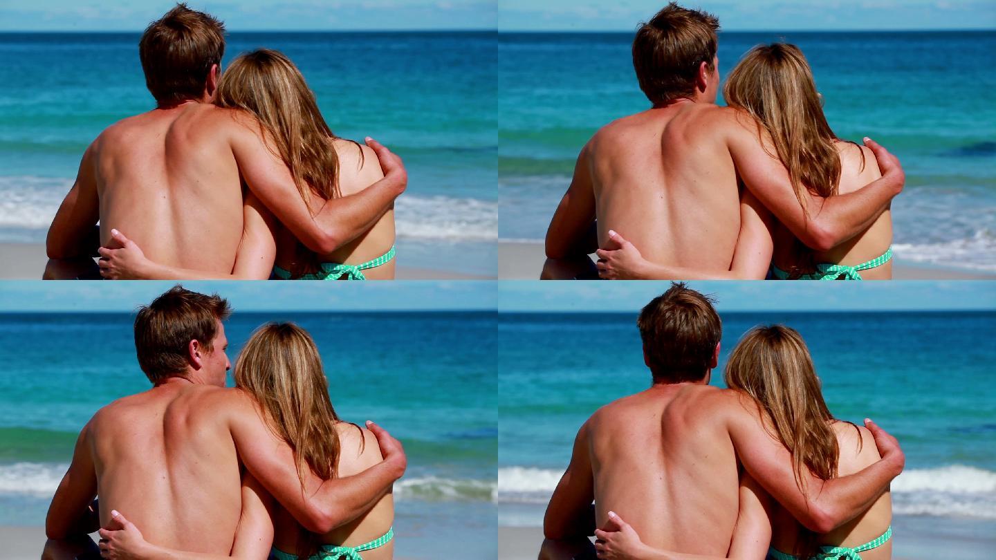 一对情侣坐在海滩上拥抱