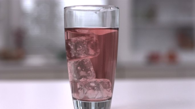 慢镜头中，四个冰块在一杯果汁中旋转