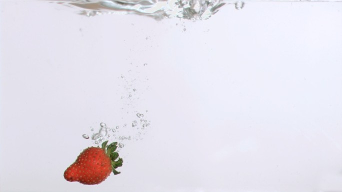 美味的草莓在超级慢动作下降在白色的背景