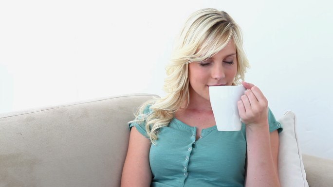 金发女人坐在沙发上喝咖啡