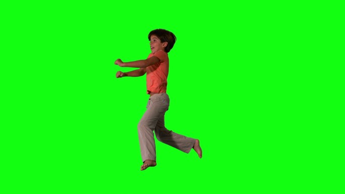 快乐男孩在绿色屏幕上跳上跳下的慢镜头