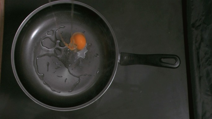 鸡蛋以超慢的动作掉进厨房的平底锅里