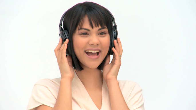 可爱的亚洲女人听音乐耳机对一个白色的背景