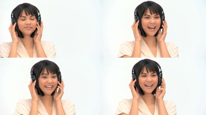 可爱的亚洲女人听音乐耳机对一个白色的背景