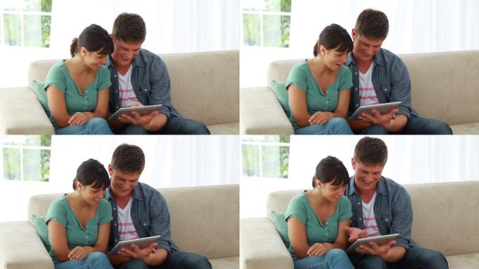 一对微笑的情侣在明亮的客厅里一起看电子书