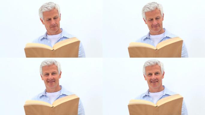 一个微笑的男人在白色的背景下读小说