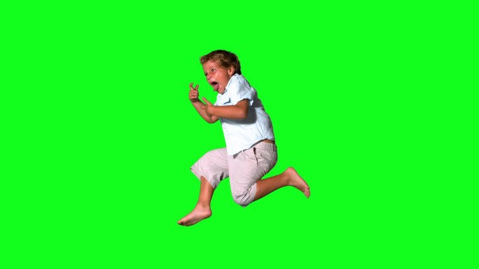 一个白人男孩跳跃在绿色背景下慢镜头