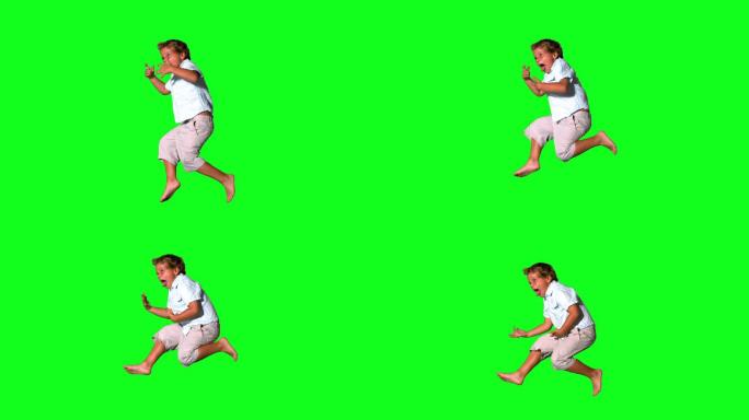 一个白人男孩跳跃在绿色背景下慢镜头