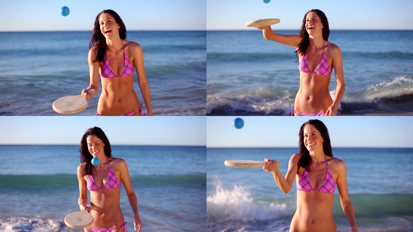 微笑的黑发女孩在沙滩上玩着划桨