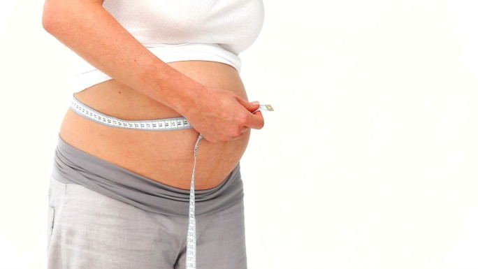 孕妇用卷尺测量自己的肚子，在白色背景下