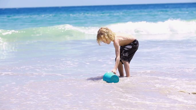 金发碧眼的小女孩在海滩上装满了水