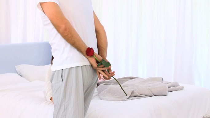 一个成熟的男人在卧室里向妻子献上一支玫瑰