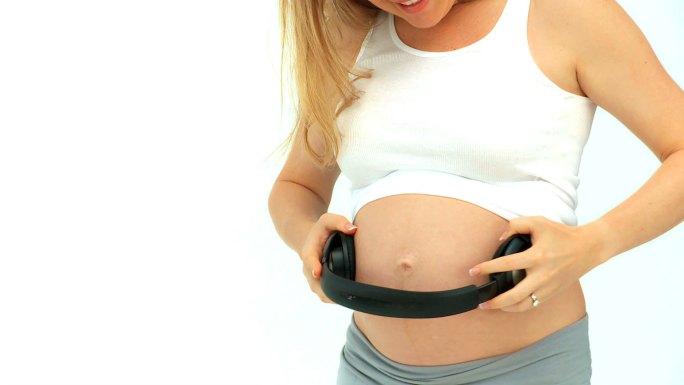 一个孕妇在肚子上戴上耳机
