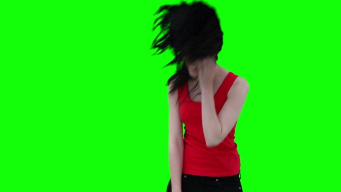 一个女人弯着腰，在绿色的背景下挥动着她的头发