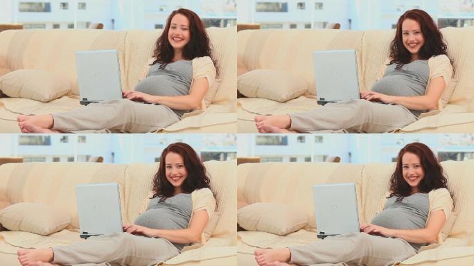 一个孕妇在客厅用笔记本电脑聊天