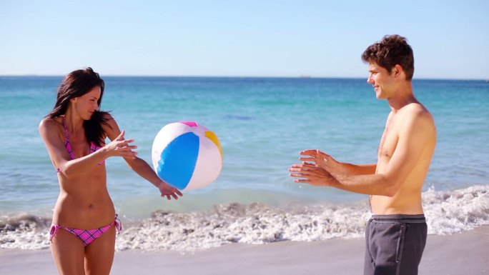 一对快乐的夫妇在沙滩上玩沙滩球