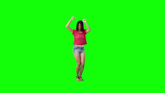 一个年轻女子在绿色的背景下独自跳舞