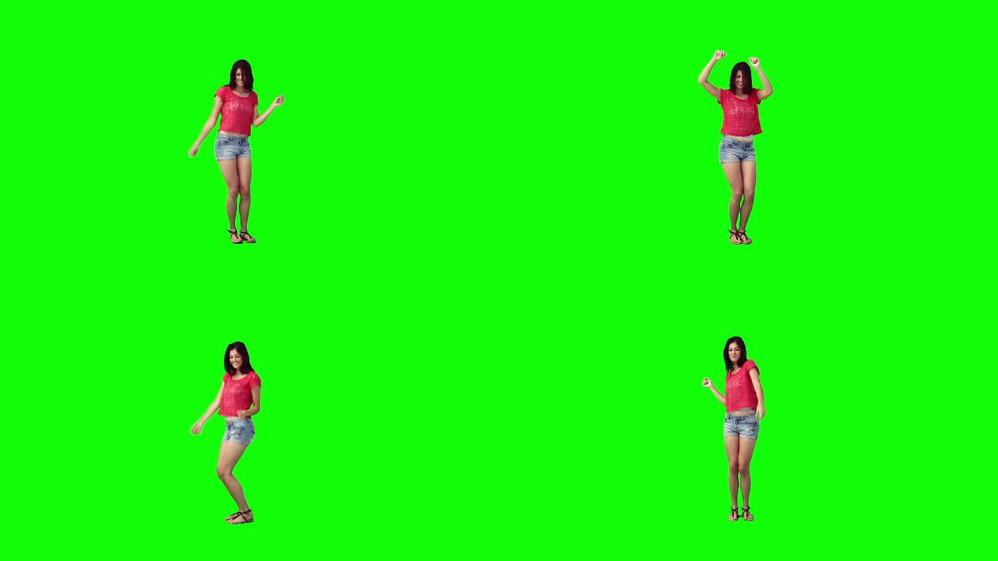 一个年轻女子在绿色的背景下独自跳舞