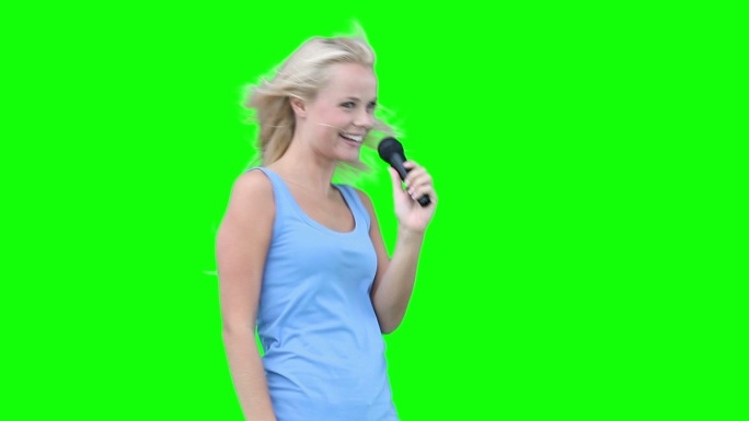 一个金发女人在绿色背景下对着麦克风唱歌